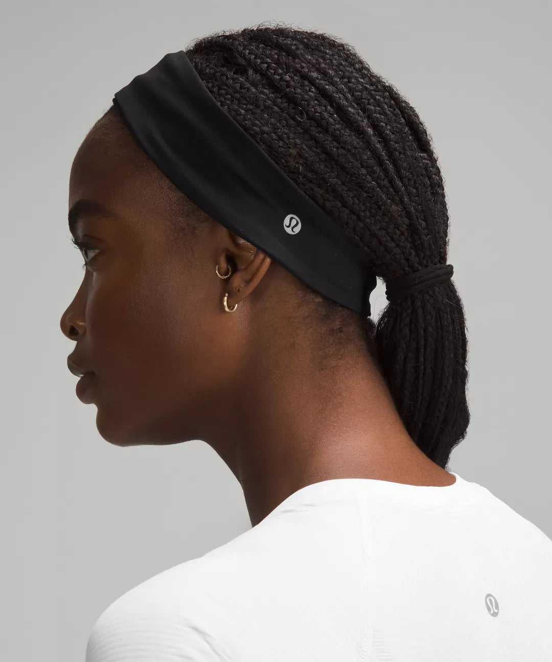 Woman wearing a black headband with a brand logo on a gray background